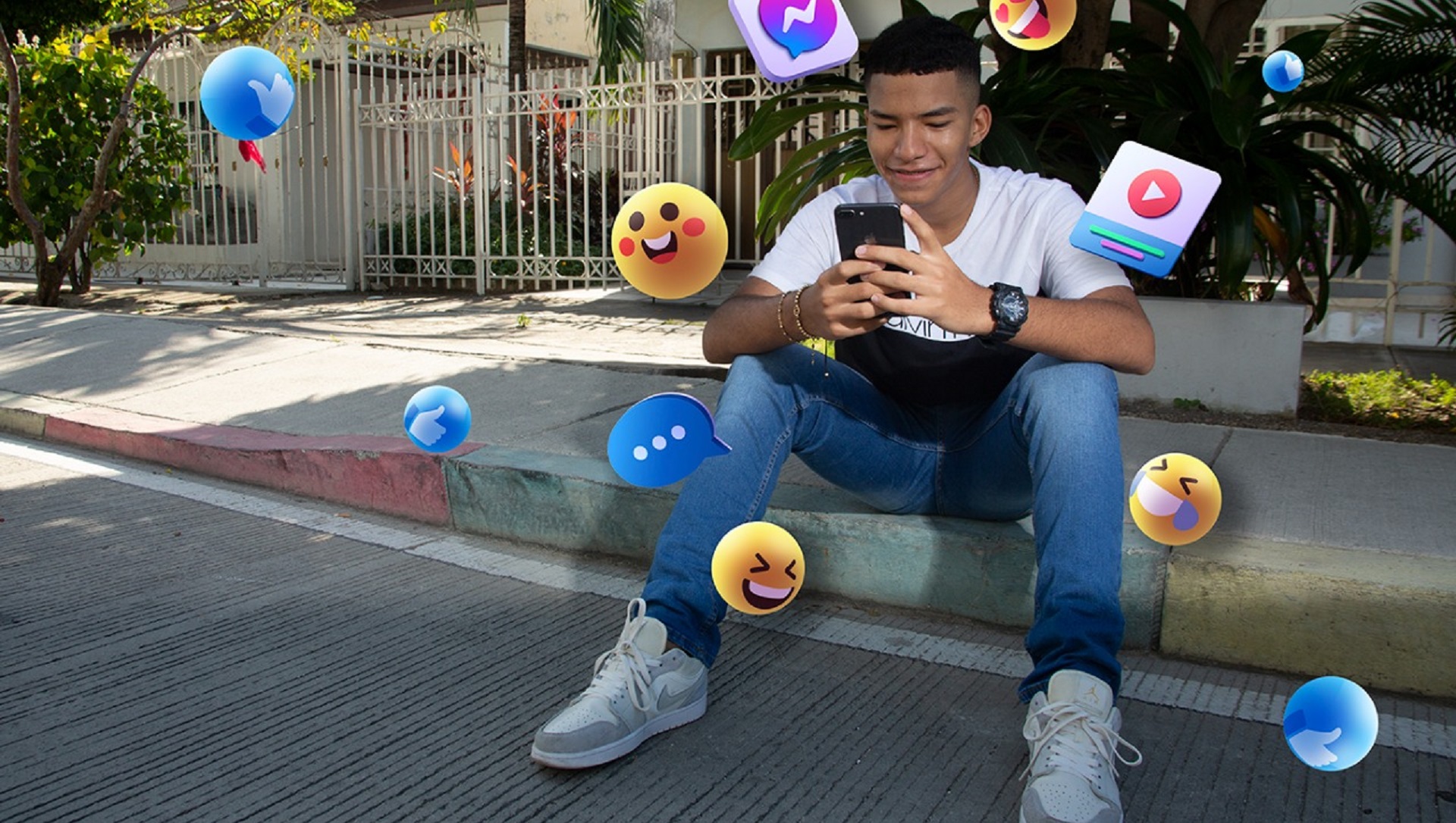 Imagen: Joven sentado bajo un árbol sostiene un celular en la mano y sonríe. Banco de imágenes MinTIC. Imagen: Joven sentado bajo un árbol sostiene un celular en la mano y sonríe. Banco de imágenes MinTIC.
